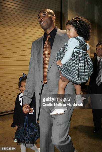 Kobe Bryant of the Los Angeles Lakers walks out of the arena with his daughters Natalia and Gianna following his team's victory over the Boston...