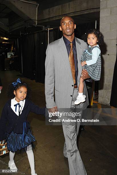 Kobe Bryant of the Los Angeles Lakers walks out of the arena with his daughters Natalia and Gianna following his team's victory over the Boston...