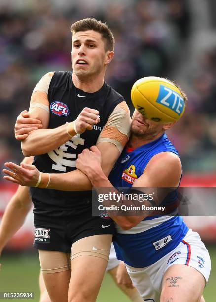 Marc Murphy of the Blues handballs whilst being tackled by Tom Liberatore of the Bulldogs during the round 17 AFL match between the Carlton Blues and...