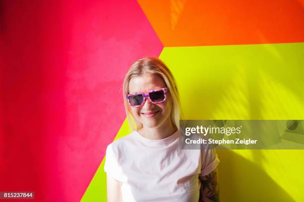 young woman in front of colorful background smiling - leuchtende farbe stock-fotos und bilder
