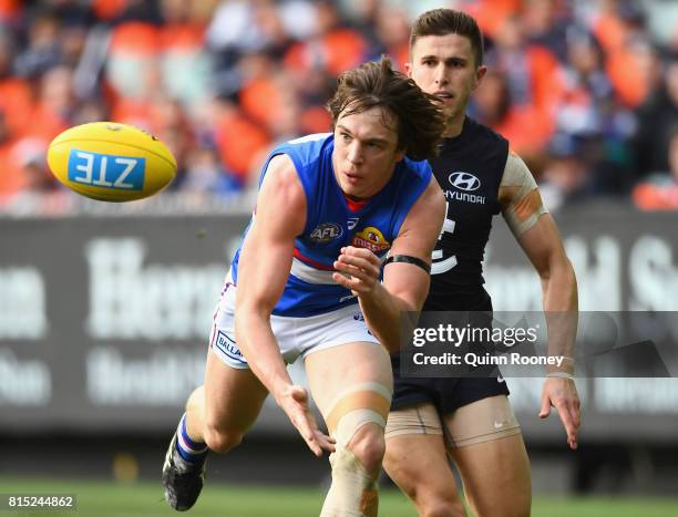 Liam Picken of the Bulldogs handballs whilst being tackled by Marc Murphy of the Blues during the round 17 AFL match between the Carlton Blues and...