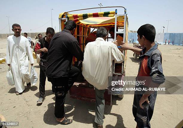 Iraqis climb aboard a 'satuta', a cart pulled by a motorcycle, in front of a cement block security wall in the eastern Baghdad district of Sadr City...