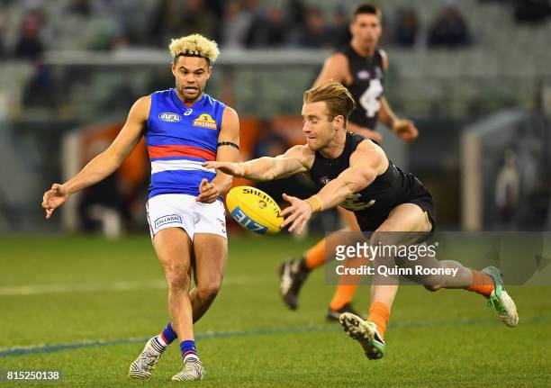 Jason Johannisen of the Bulldogs has his kick smouthered by Nick Graham of the Blues during the round 17 AFL match between the Carlton Blues and the...