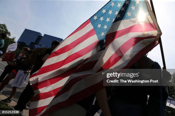 Tamara Lee, from Manhattan, NY, right, holds a flag as she protest in front of the National Rifle Association headquarters in Fairfax, Va., during a...