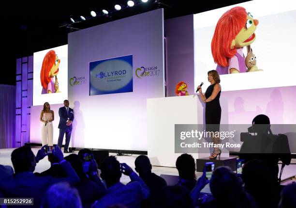 Hosts Holly Robinson Peete and Rodney Peete present the first autistic Sesame Street muppet Julia with the HollyRod Corporate Compassion Award to...