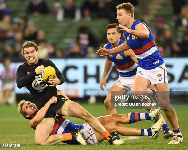 Bryce Gibbs of the Blues handballs whilst being tackled by Mitch Wallis of the Bulldogs during the round 17 AFL match between the Carlton Blues and...