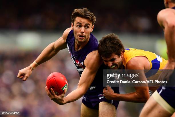 Lachie Weller of the Dockers handpasses the ball under pressure from Andrew Gaff of the Eagles during the 2017 AFL round 17 match between the...