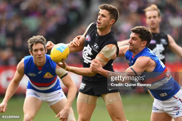 Marc Murphy of the Blues handballs whilst being tackled by Tom Liberatore of the Bulldogs during the round 17 AFL match between the Carlton Blues and...