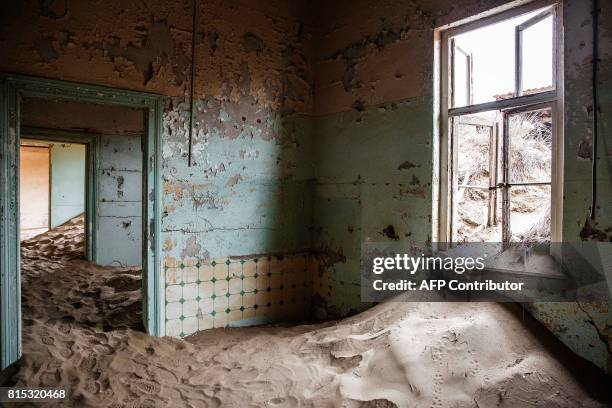 Picture taken on June 27, 2017 shows an abandoned house filled with sand, in the deserted mining town of Kolmanskop, in Luderitz, Namibia. The...