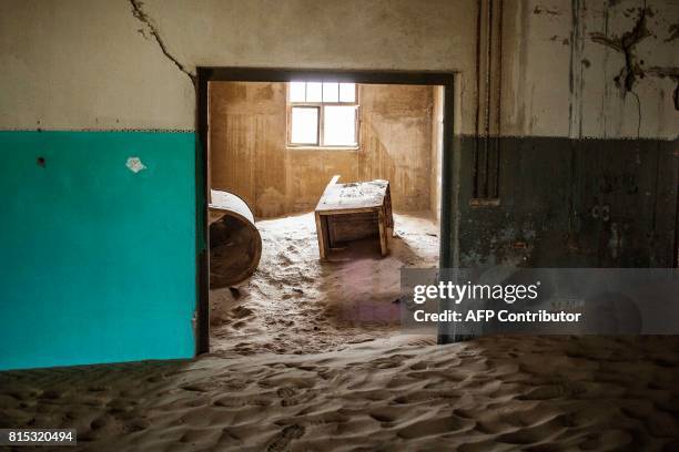 Picture taken on June 27, 2017 shows an abandoned house filled with sand, in the deserted mining town of Kolmanskop, in Luderitz, Namibia. The...