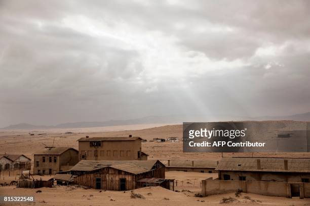 Picture taken on June 27, 2017 shows abandoned houses covered with sand, in the deserted mining town of Kolmanskop, near Luderitz, Namibia. For the...