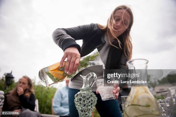 young woman pouring water from a jar - sparkling water photos et images de collection