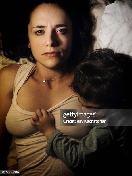 young woman looking into camera as toddler sleeps - innocence stockfoto's en -beelden