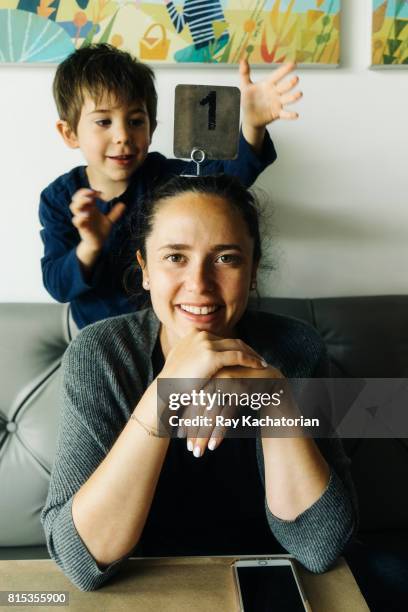 young boy holds number 1 sign on mother head - family housing 2017 awards inside stock-fotos und bilder