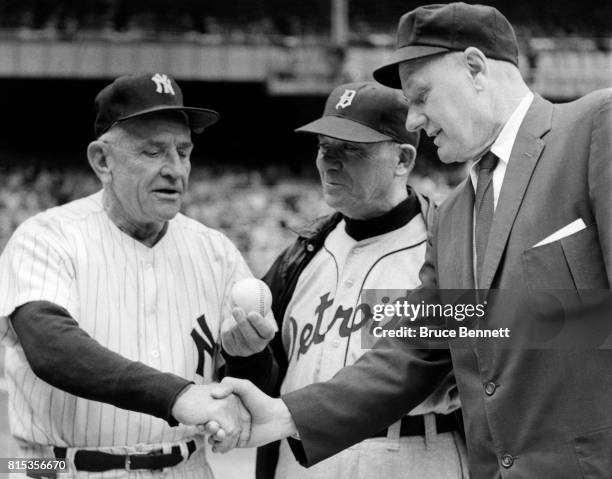 Manager Casey Stengel of the New York Yankees is congratulated by umpire Edwin A. Rommel and manager Jimmy Dykes of the Detroit Tigers, as he holds...