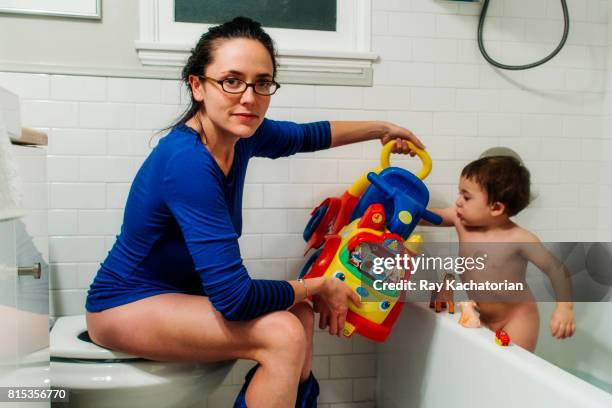 mother holds child toy while sitting on toilet - childrens closet stockfoto's en -beelden