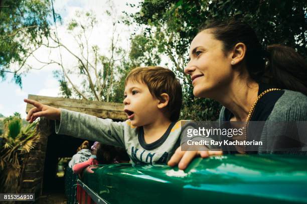 child points as mother looks on while on train - 長袖 ストックフォトと画像
