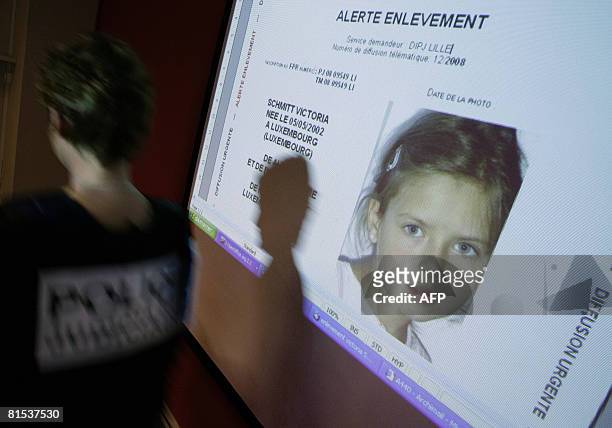 Policewoman passes in front of a screen where an international simulated kidnapping alert is projected for the media to test the "Plan Alerte...