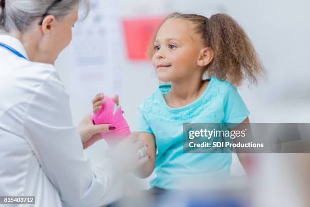 pediatric orthopedic doctor puts cast on girl's arm - orthopaedic equipment stock pictures, royalty-free photos & images