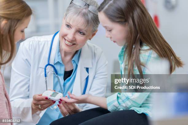 doctor checks young patient's blood sugar level - endocrine system stock pictures, royalty-free photos & images