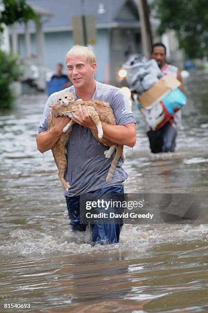 Brandon Smith carries his two cats, Fry and Bender, to dry land from their flooded and evacuated home on June 12, 2008 in Cedar Rapids, Iowa. Much of...