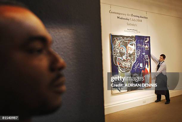 Security guard stands in the doorway while a gallery assistant adjusts the painting "Untitled " by Jean-Michel Basquiat at Sotheby's on June 12, 2008...