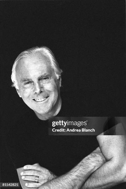 Italian fashion designer Giorgio Armani smiles as he poses with his arms crossed, early 1990s.