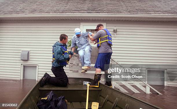 Tom Van Hoe is rescued from his flooded home by Justin Jensen of the Cedar Rapids Fire Department and Jake Siggins of the Lisbon, Iowa Fire...