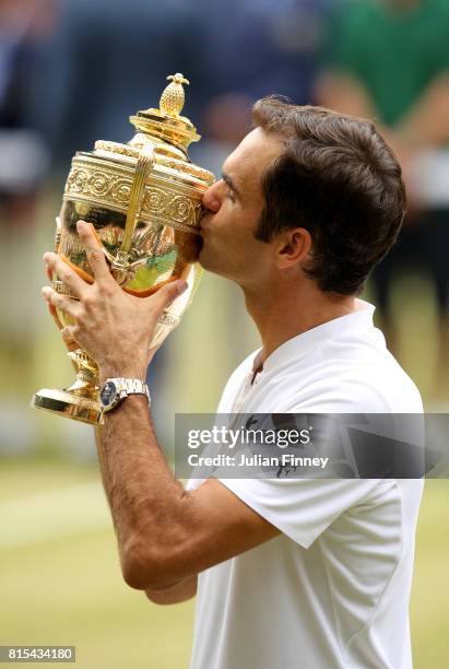 Roger Federer of Switzerland kisses the trophy as he celebrates victory after the Gentlemen's Singles final against Marin Cilic of Croatia on day...