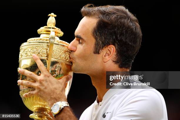 Roger Federer of Switzerland kisses the trophy as he celebrates victory after the Gentlemen's Singles final against Marin Cilic of Croatia on day...