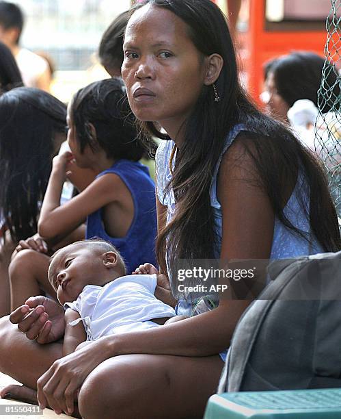 Philippines-homeless-children-streets" by Jason Gutierrez A woman street dweller holds her baby while other children gather around in Manila's...