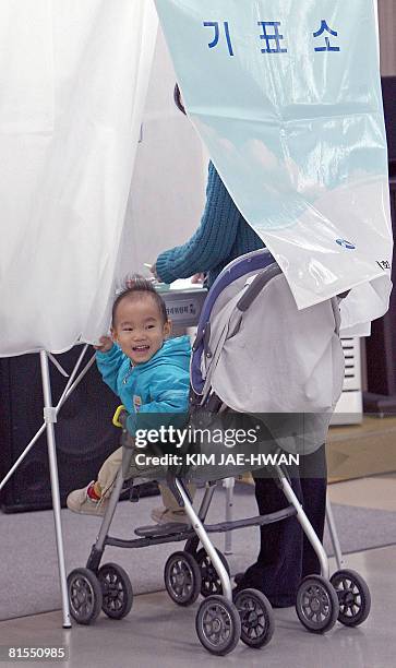 Baby smiles while his parent casts a vote in the South Korean general elections in Seoul on April 9, 2008. South Koreans went to the polls to elect a...