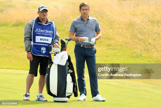 Robert Rock of England looks down the 18th hole with caddie Kyle Roadley during the final round of the AAM Scottish Open at Dundonald Links Golf...