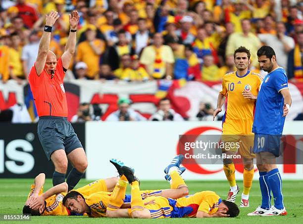 Razvan Rat , Paul Codrea and Mirel Radoi of Romania all lie on the ground after a collision as referee Tom Henning Ovrebo of Norway signals to the...