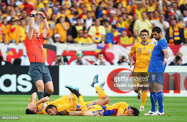 Razvan Rat , Paul Codrea and Mirel Radoi of Romania all lie on the ground after a collision as referee Tom Henning Ovrebo of Norway signals to the...