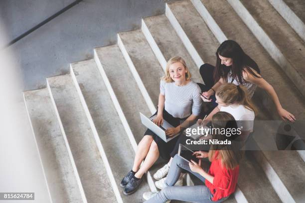 jung und glücklich urbane menschen halten technologien beim sitzen auf stufen - student stock-fotos und bilder