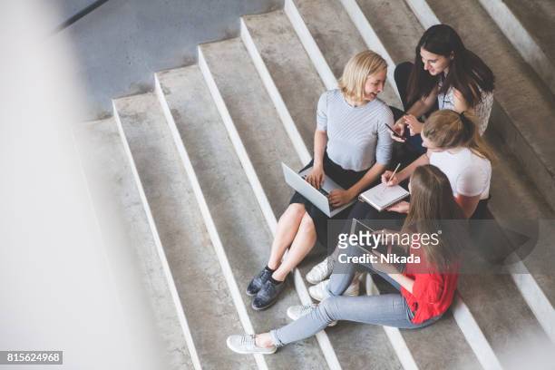 junge freundinnen mit technologien auf schritte im freien sitzend - student stock-fotos und bilder