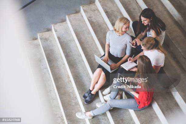 jóvenes amigas utilizando tecnologías sentado en pasos al aire libre - adult student fotografías e imágenes de stock