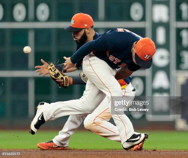 Marwin Gonzalez of the Houston Astros can't cleanly make a play on a ground ball as Alex Bregman passes in front of him against the Minnesota Twins...