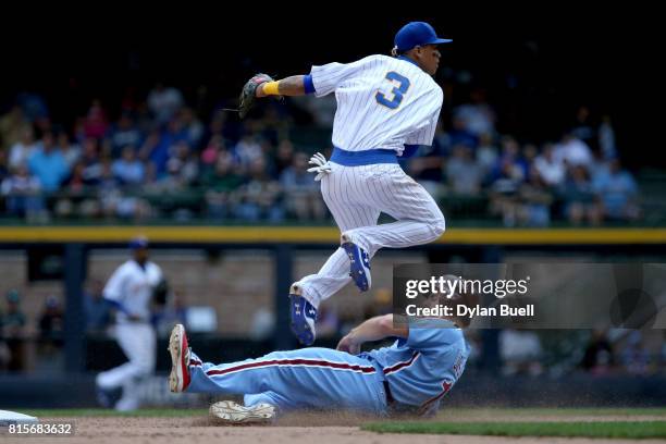 Orlando Arcia of the Milwaukee Brewers turns a double play past Andrew Knapp of the Philadelphia Phillies in the seventh inning at Miller Park on...