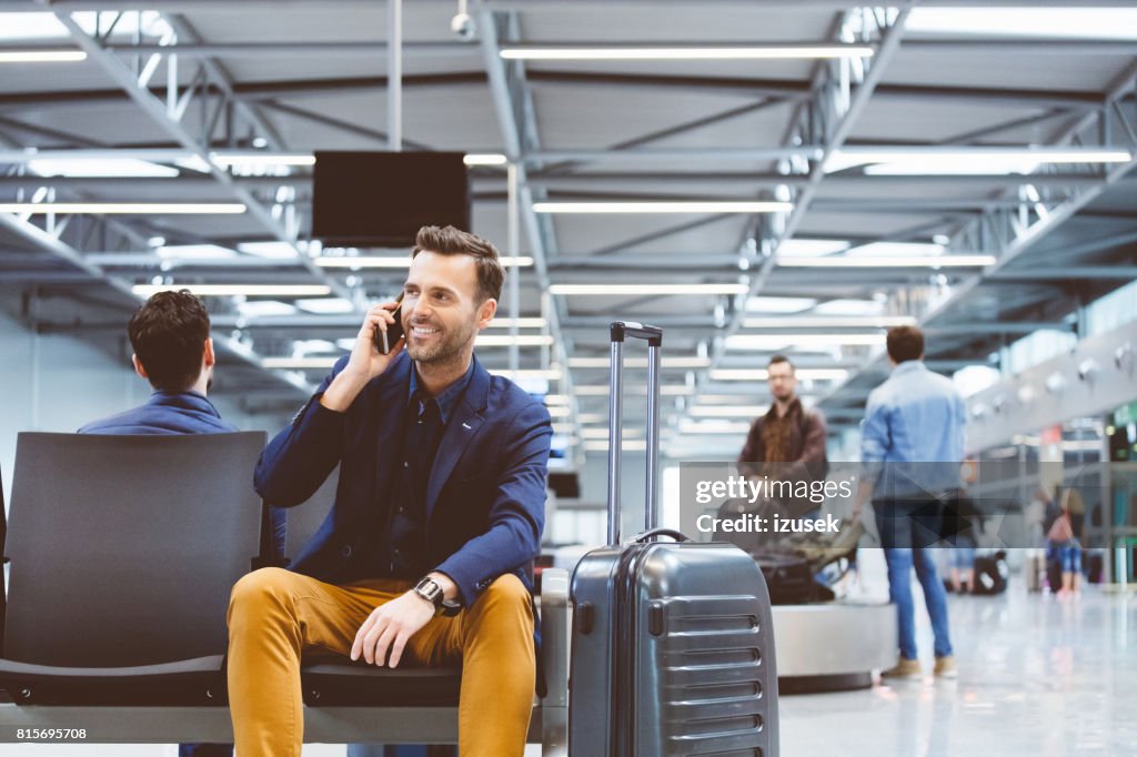 Homem no saguão do aeroporto e usando telefone celular