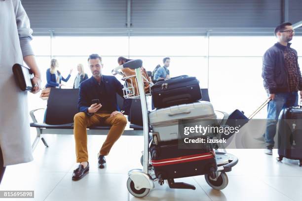 volwassen man te wachten op de luchthaven lounge - luggage trolley stockfoto's en -beelden