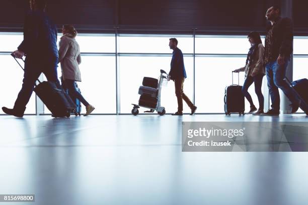 silhouet van mensen lopen met bagage in de luchthaventerminal - luggage trolley stockfoto's en -beelden