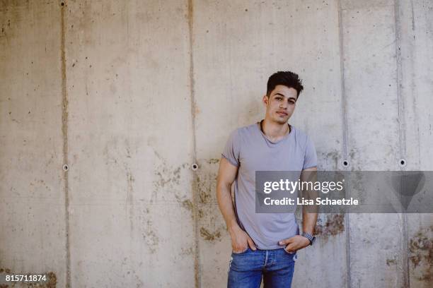 portrait of a young man leaning on a wall - fugitive fotografías e imágenes de stock