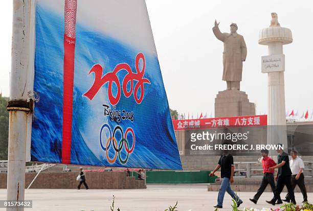 Uighur Muslims walk across People's Square with Olympics decorations near the statue of Communist China's former leader Mao Zedong that stands in...