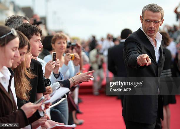 French actor Lambert Wilson gestures on the red carpet as he arrives at the 22nd Romantic Film festival ceremony in Cabourg, northwestern France, on...