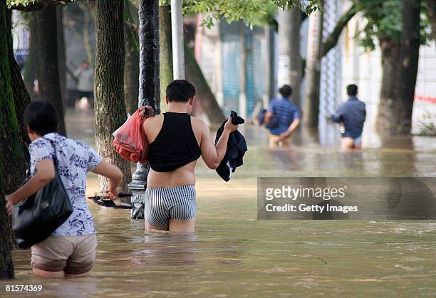 People are walking on the flooded street after rainstorms on June 13 in Yongzhou, Hunan Province China. A dozen people were killed and millions were...