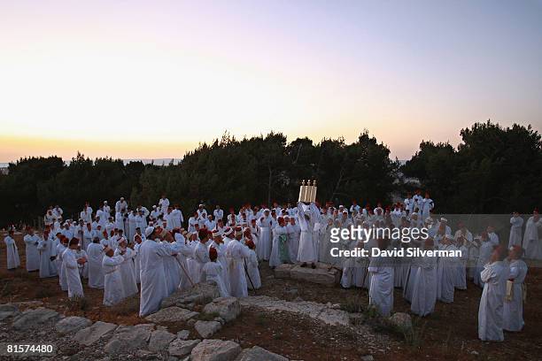 Samaritan High Priest Elazar ben Tsedaka ben Yitzhaq raises the Torah scroll as members of the sect pray at dawn on the festival of Shavuoth, which...