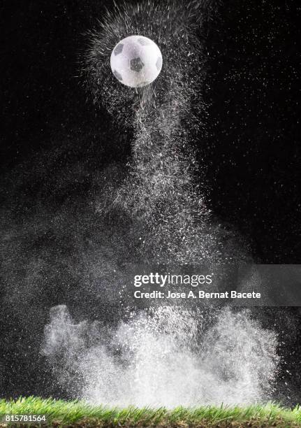 impact and rebound of a ball of football on a surface of land and powder on a black background - bounce photos et images de collection