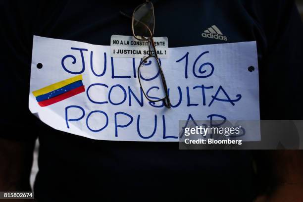 Man wears a sign reading "July 16 Popular Consultation" in Spanish during a symbolic Venezuelan plebiscite in Caracas, Venezuela, on Sunday, July 16,...